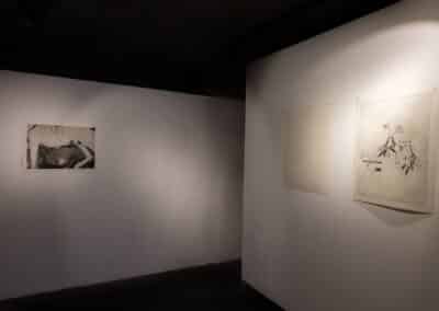 Installation view of three photo intaglio prints hung on adjoining walls. The prints are illuminated by spotlights.