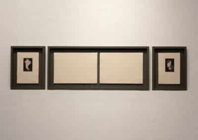 Two blind embossing prints framed in one large black frame on a white wall. These are flanked by two small black and white etchings in black frames.