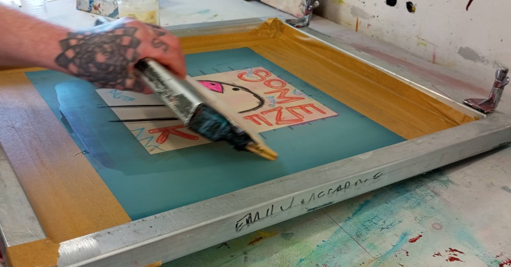 Squeege pulling ink through a screen.