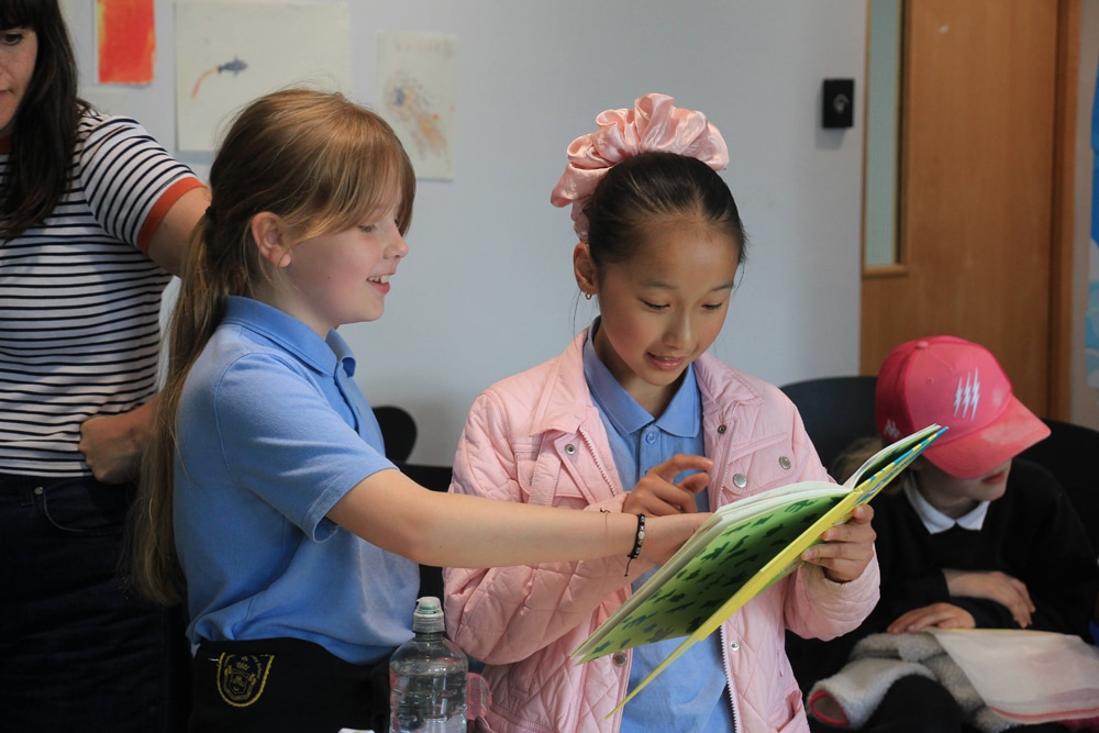 Two girls looking at the book The Dangerous School Tour for the first time